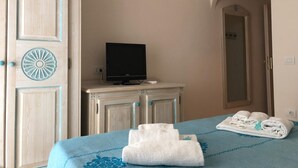 Una habitación de hotel con una cama, un televisor sobre un mueble de madera y un espejo en la pared.