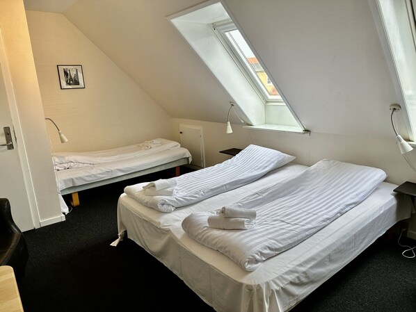 A dormitory room with two single beds, a skylight, a small desk, and a picture on the wall. - Foldens Bed & Breakfast (Skagen)
