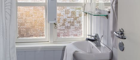 Een badkamer met een raam, een wastafel en een toilet.