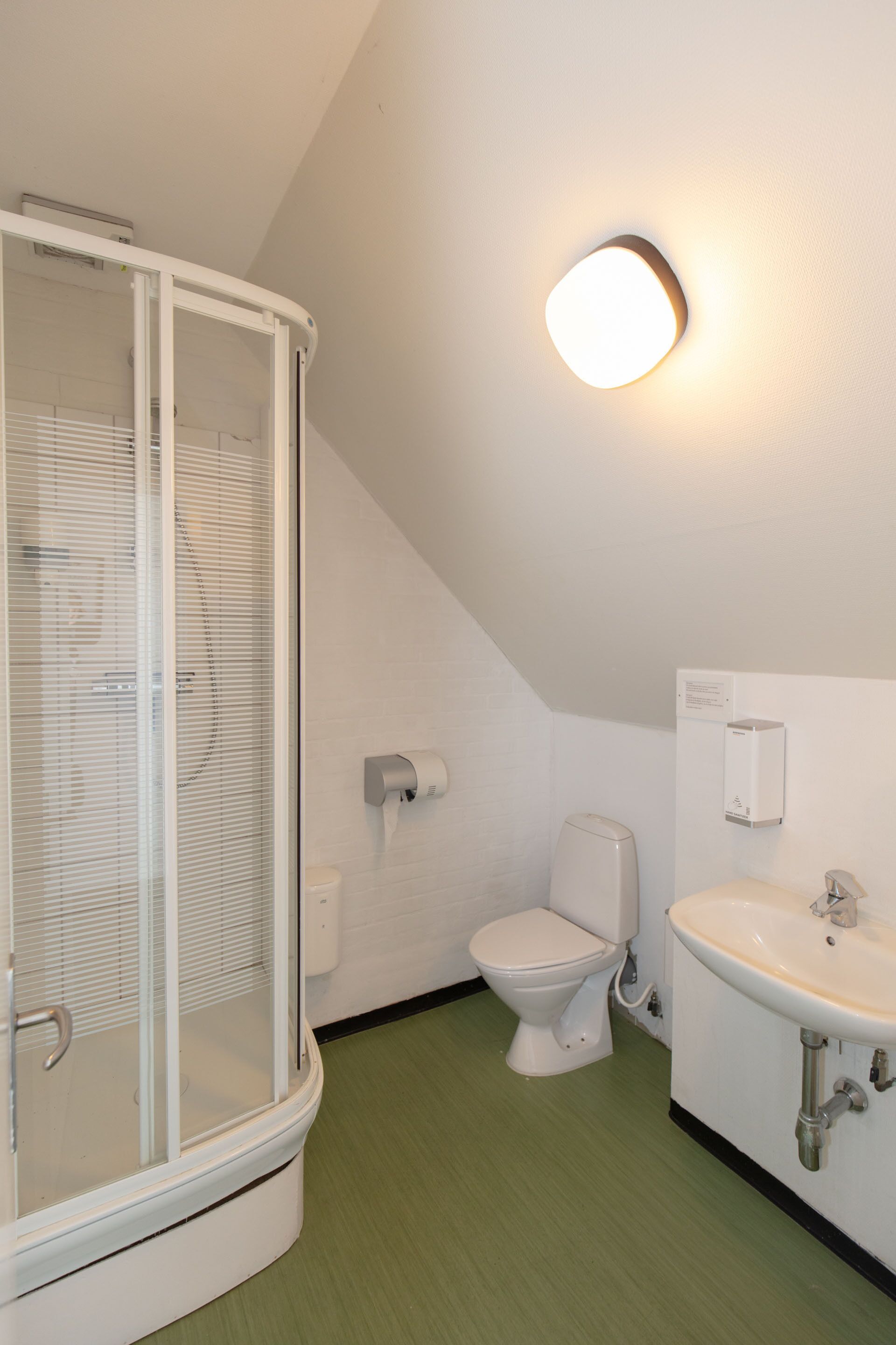 Et badeværelse med bruseniche, toilet og håndvask.