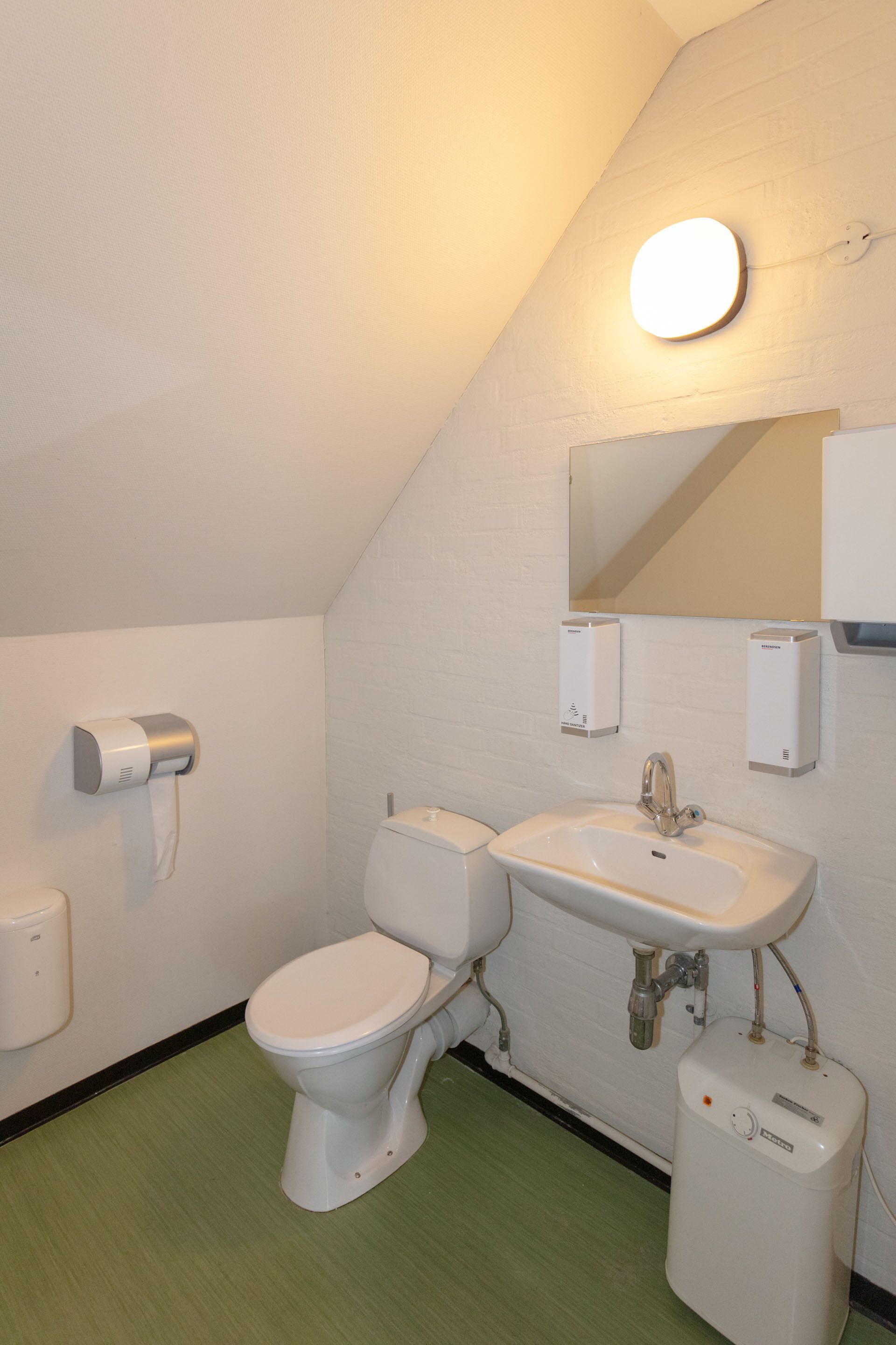 Une salle de bain équipée de toilettes, d’un lavabo et d’un sèche-mains.