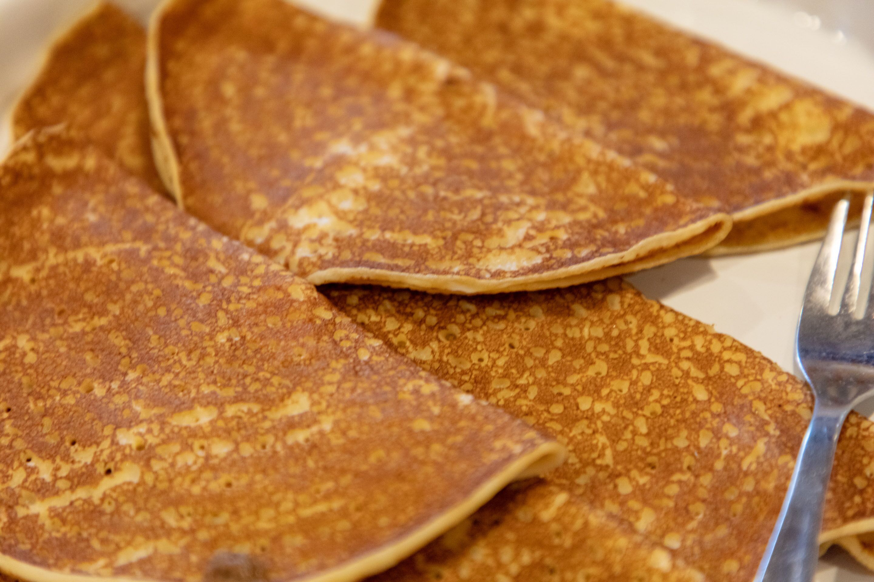 A plate of golden-brown pancakes with a fork.