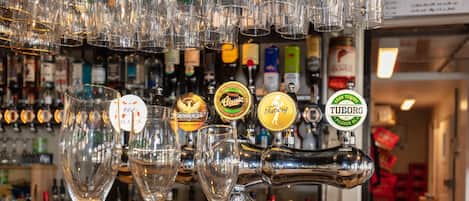 A bar with multiple taps and glasses.