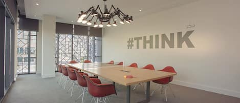 A conference room with a long table, red chairs, and a chandelier.