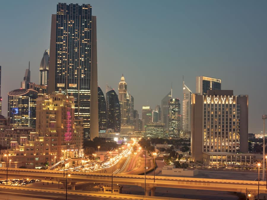 A cityscape with high-rise buildings, including a hotel with "ROYAL" illuminated on its facade.