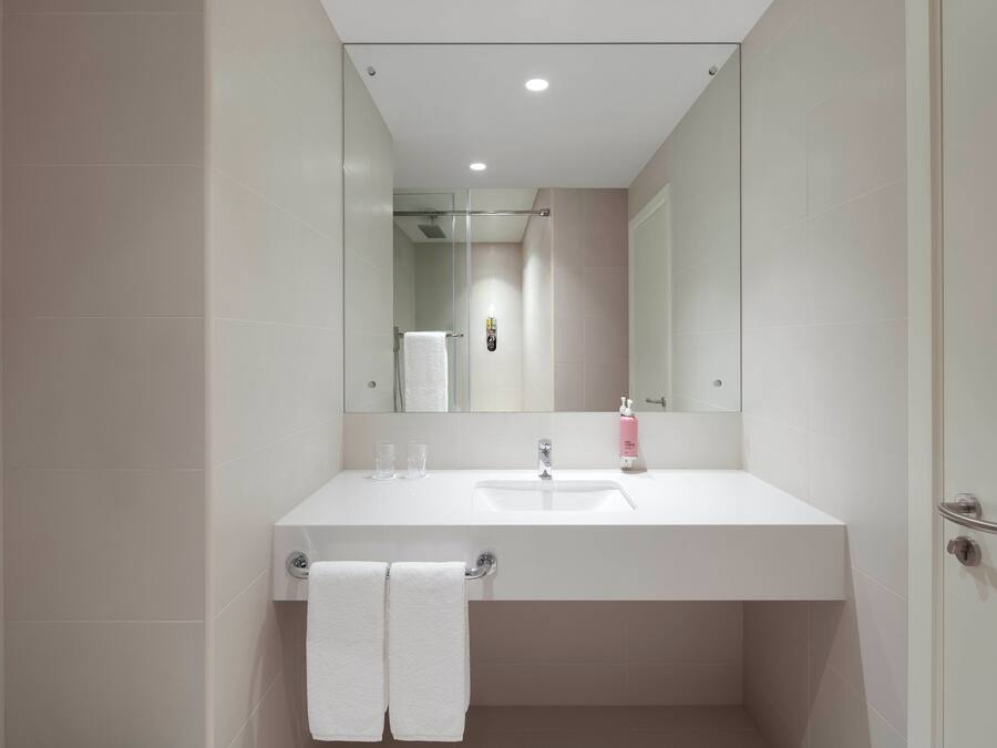 Une salle de bain moderne avec un lavabo blanc, un miroir et un porte-serviettes.