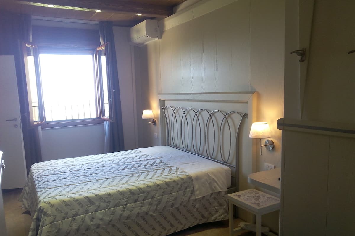 Een slaapkamer met een bed, nachtlampjes, een raam en een airconditioner.