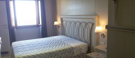 A bedroom with a bed, bedside lamps, a window, and an air conditioning unit.