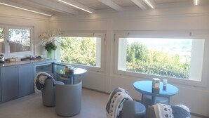 A modern kitchen with a dining area, large windows, and a view of greenery. - IL POGGETTO DI MERLI SILVIA & C. SAS (Tavoleto)