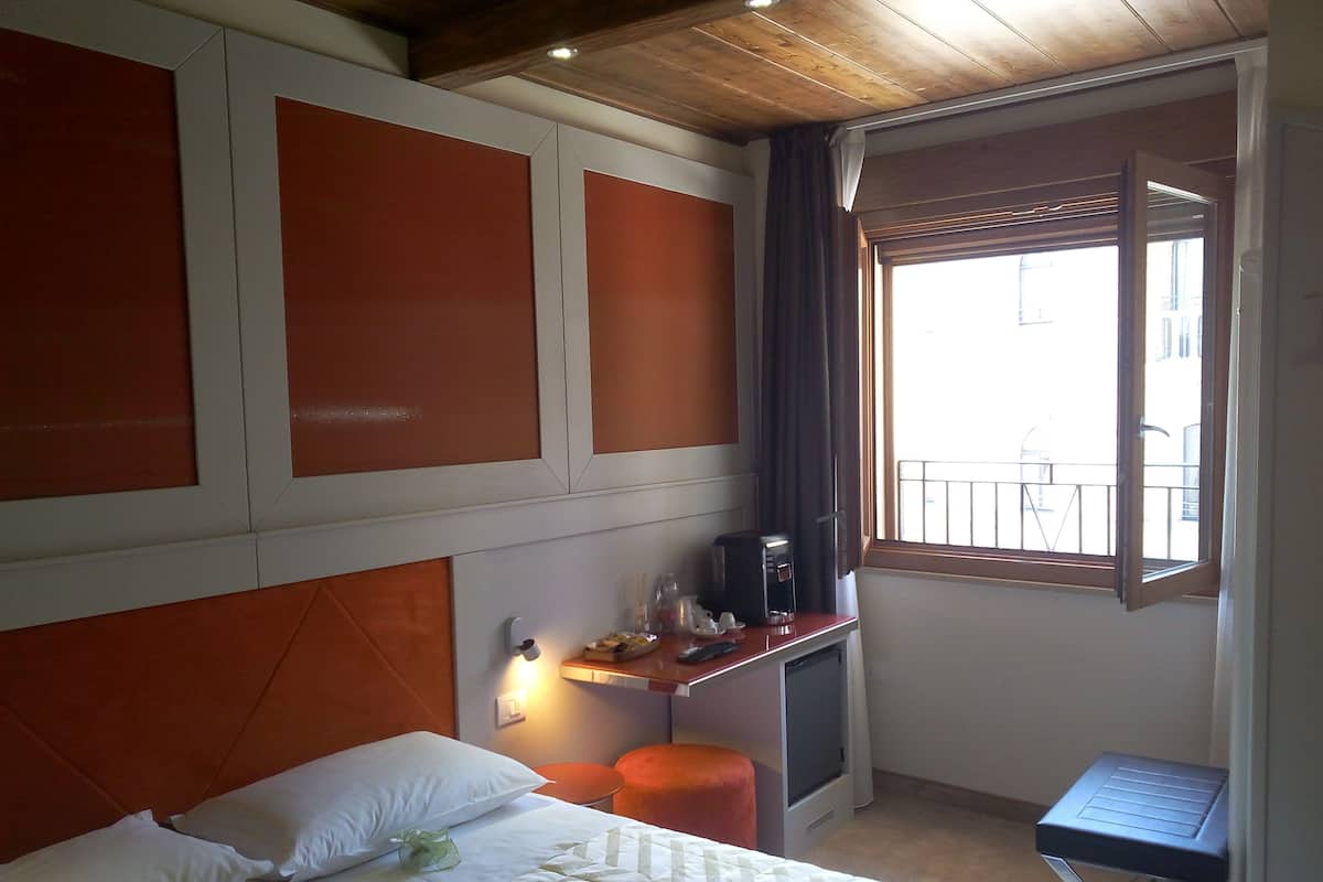 Een hotelkamer met een bed, een kleintje tafeltje met een koffiezetapparaat, een televisie en een raam met uitzicht op het omliggende landschap.