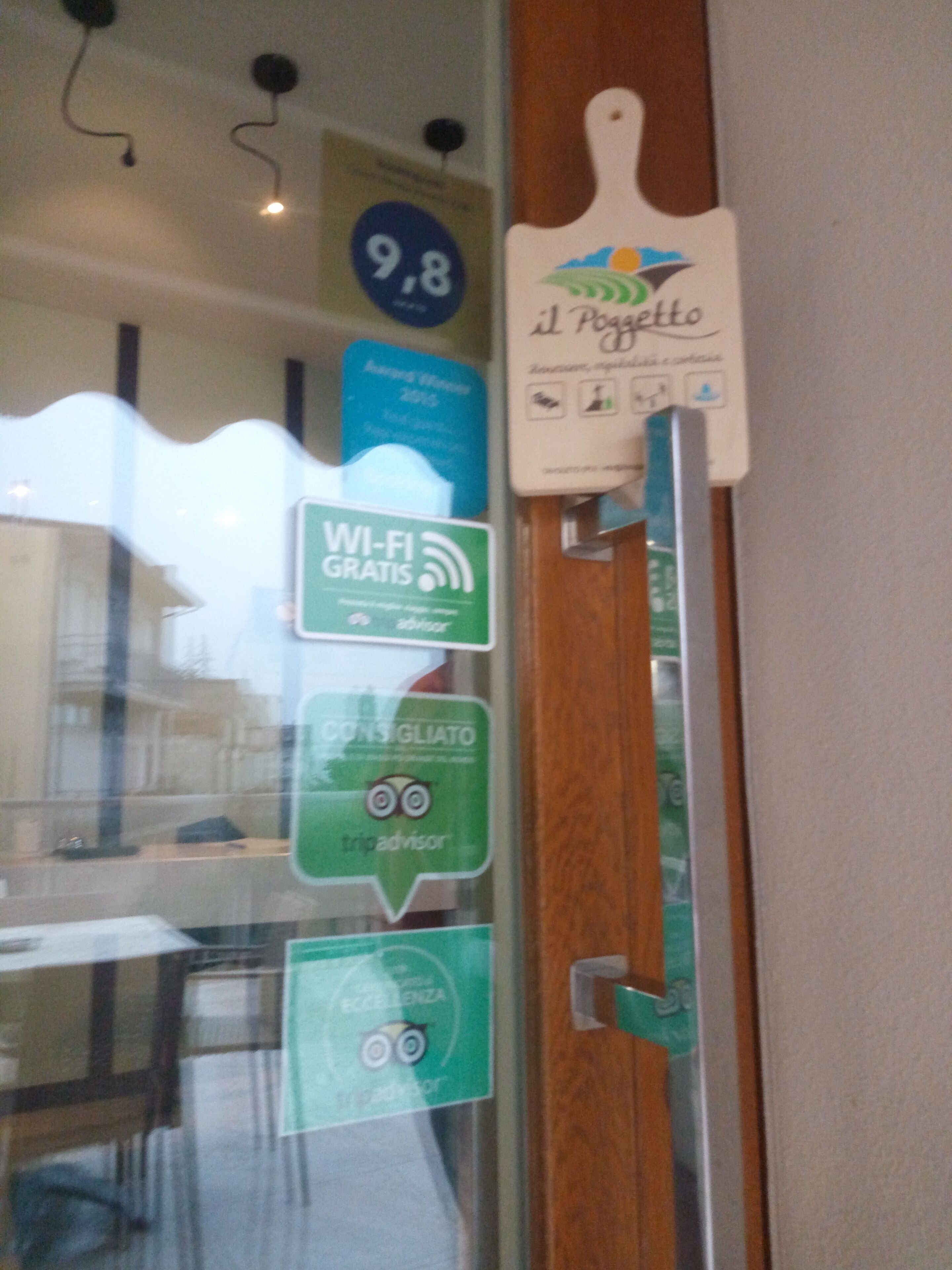A glass door with various signs, including a Wi-Fi symbol, a sign for free Wi-Fi, and a sign for a trip advisor.