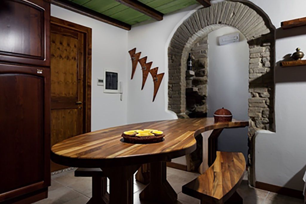 Una mesa de madera con un pastel, un arco de piedra y un ambiente de cocina rústica.
