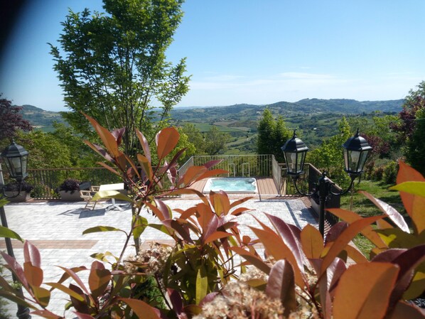 Zona de piscina con vistas al campo, rodeada de plantas y mobiliario exterior.