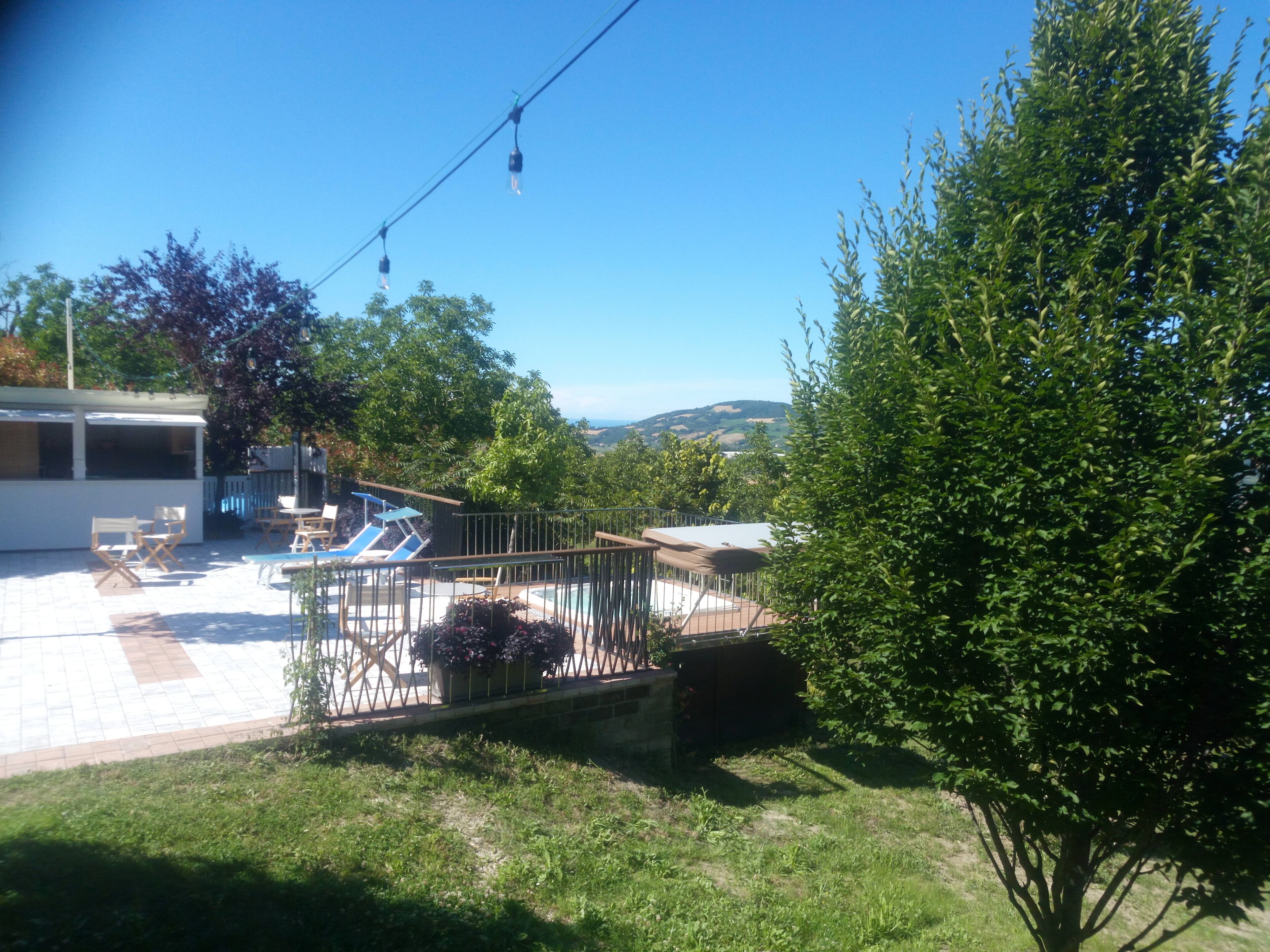 Un patio trasero con piscina, sillas de descanso y un área de patio techada.