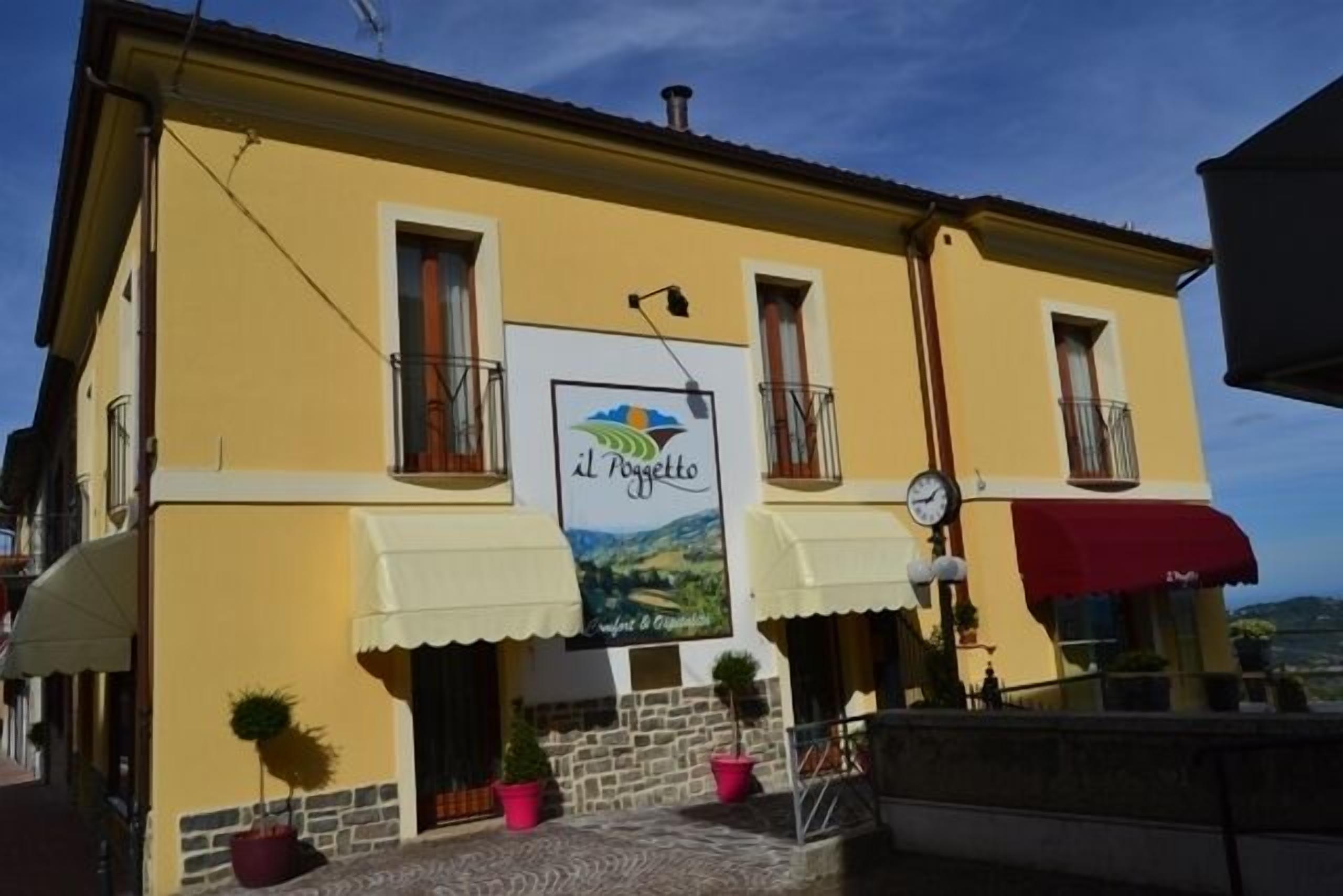A yellow building with a sign reading "Il Poggetto" and a view of the countryside.