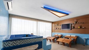 A modern bathroom with a blue bathtub, wooden loungers, a mounted TV, and a shelf with decorative items. - IL POGGETTO DI MERLI SILVIA & C. SAS (Tavoleto)