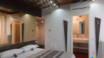 A bedroom with a large bed, a mirror, and a bathroom visible through an open door.