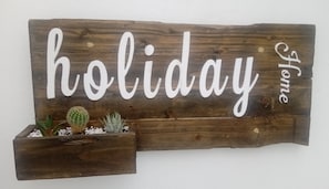 A wooden sign with the words "holiday home" and a small planter with cacti. - Residencia Praia Norte - AL (Nazaré)