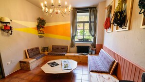 A cozy living room with a wooden bench, a round coffee table, and a chandelier. - Albergue Cueva de Valporquero (Vegacervera)