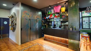 A modern bar area with a wooden counter, metal cabinets, and colorful hanging pots. - Albergue Cueva de Valporquero (Vegacervera)