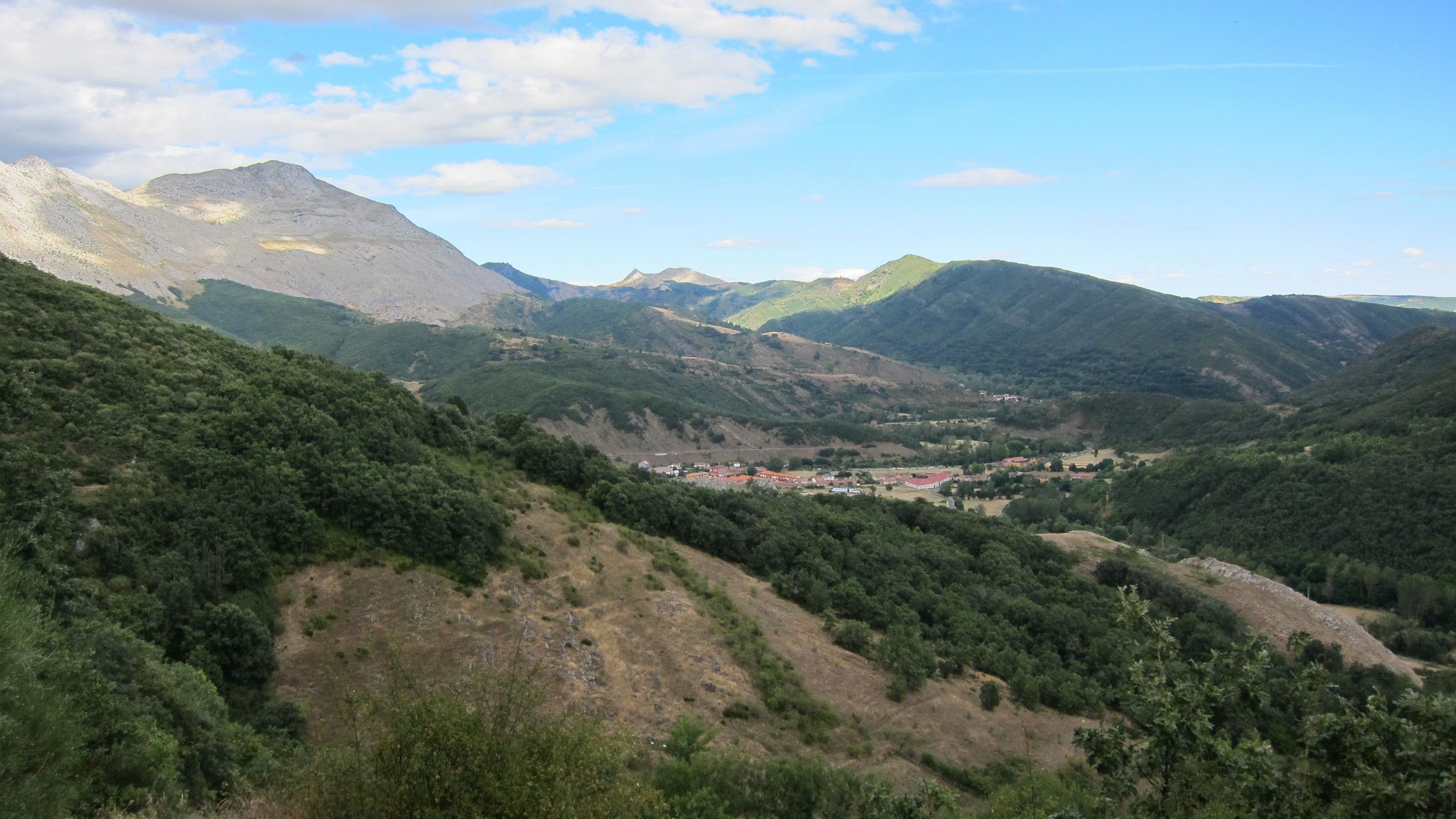 A valley with a small settlement surrounded by mountains.
