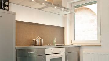 A modern kitchen with stainless steel appliances, a window with a view, and teal flooring.