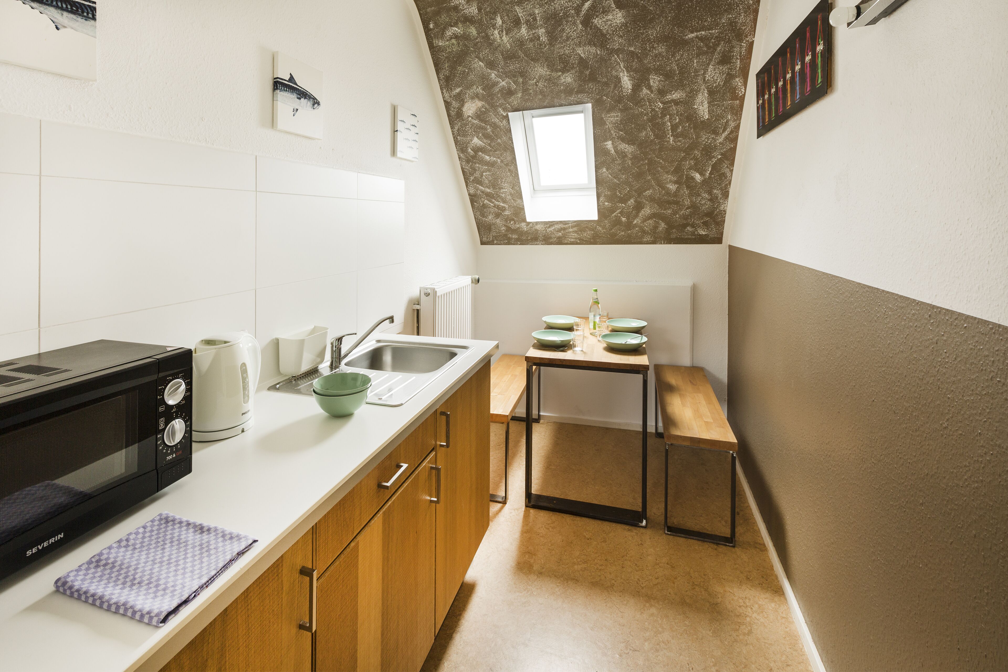 Una cocina compacta con microondas, pileta y una pequeña mesa de comedor.