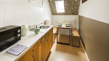 Una cocina compacta con microondas, pileta y una pequeña mesa de comedor.