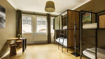 Ein Schlafsaalzimmer mit Etagenbetten, einem Schreibtisch, einem Stuhl, einer Pendelleuchte und einem Poster an der Wand.