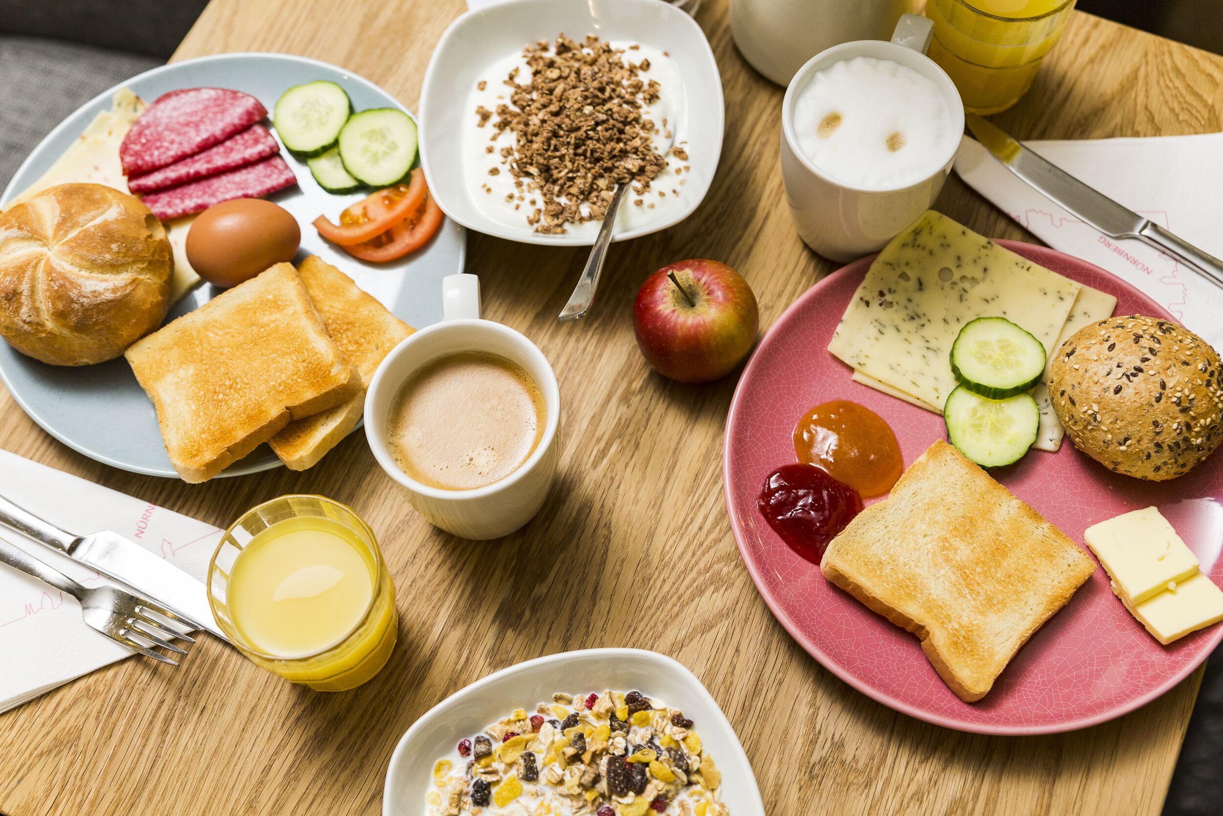A breakfast table with various food items including toast, eggs, cereal, and fruit.