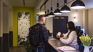 A reception desk with a modern design, a green accent wall, and a motivational poster. - Five Reasons Hotel & Hostel (Nuremberg)