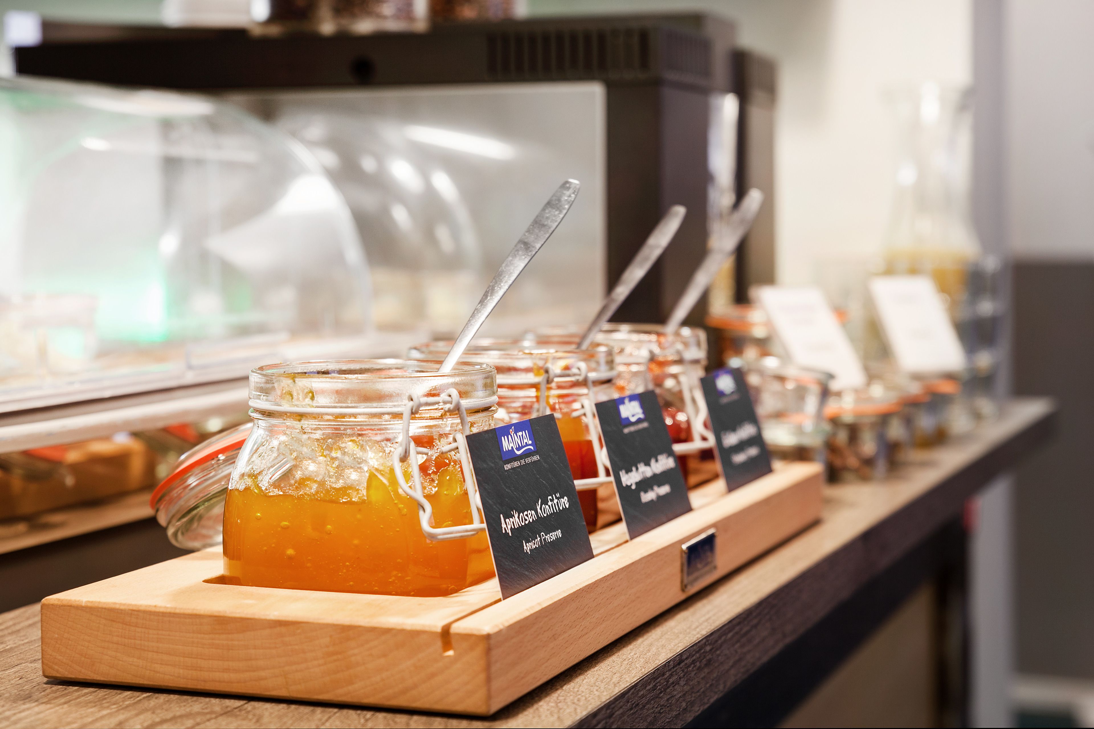 A display of honey jars with labels, a spoon, and a wooden board.