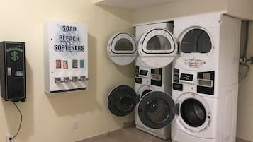 A laundry facility with multiple washing machines and a soap, bleach, and softeners dispenser.