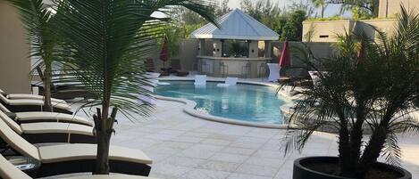 A pool area with lounge chairs and a bar.