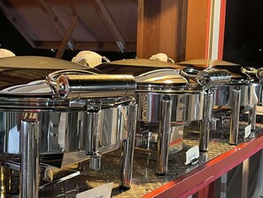 Une rangée de présentoirs de buffet en acier inoxydable, dotés de surfaces réfléchissantes et d’éléments décoratifs chromés.