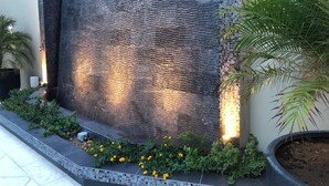 Pared texturizada con mosaicos y una planta en maceta.