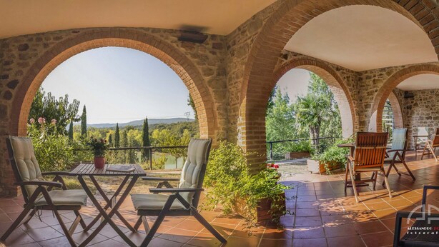 Un patio abrité, agrémenté d’arcs en pierre, d’une table et de chaises.