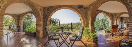 Una terrazza esterna con archi in pietra, un tavolo, sedie e piante in vaso.. Villa Sant'Anna
