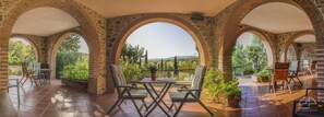 Un patio cubierto con arcos de piedra, una mesa y sillas.