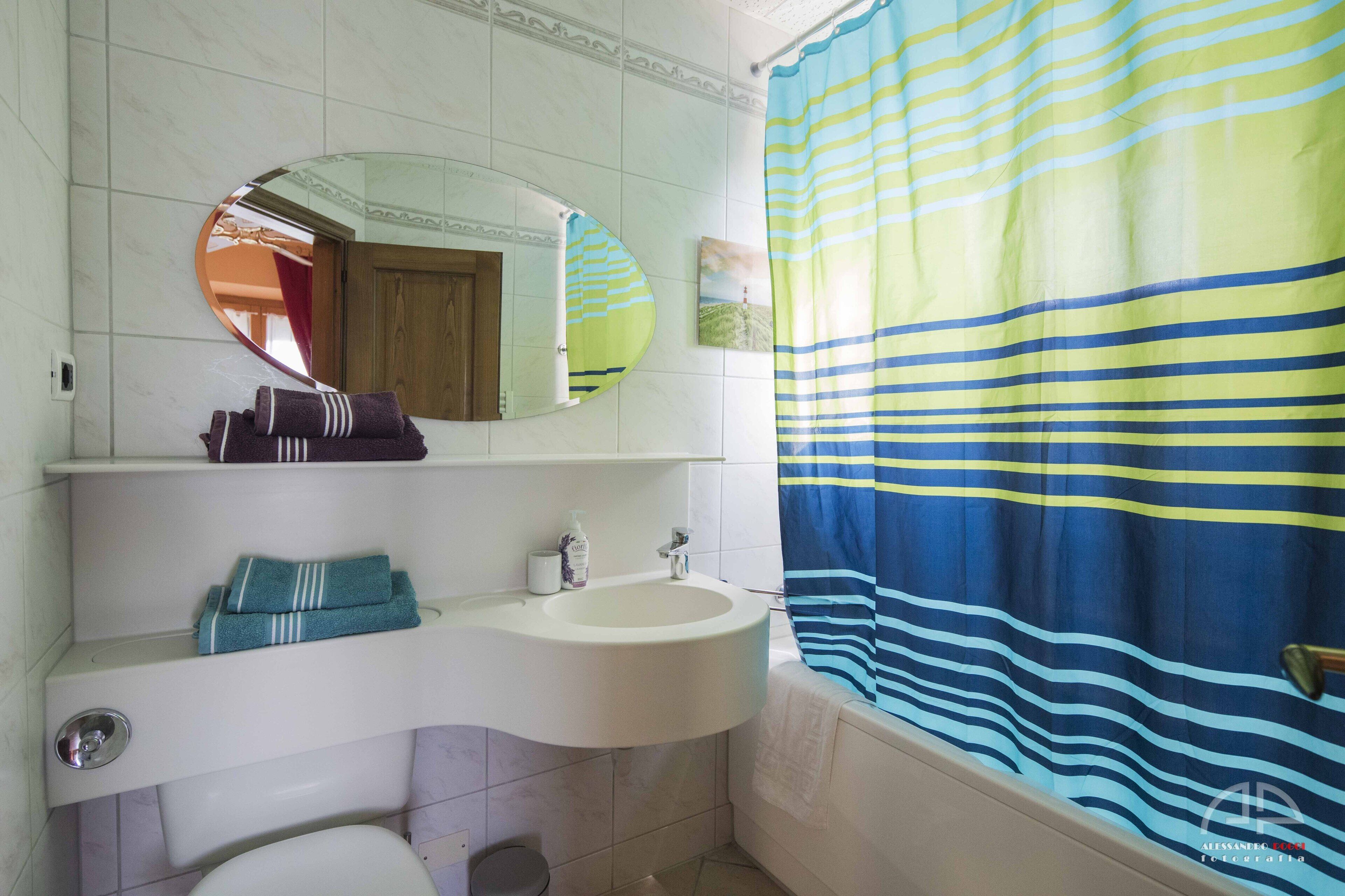 A bathroom with a white sink, a mirror, and a striped shower curtain.