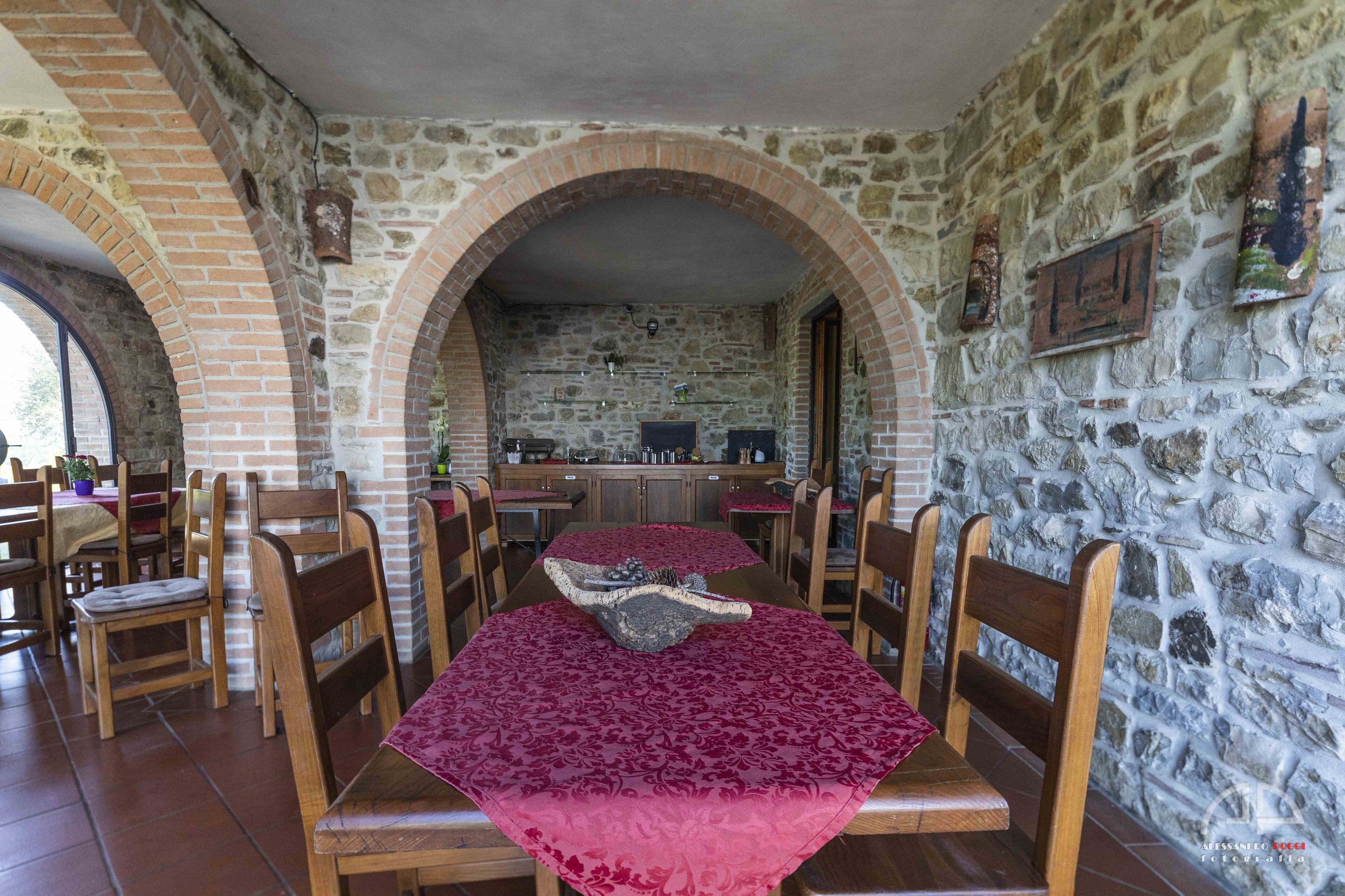 A dining area with a long table, wooden chairs, and a stone wall.