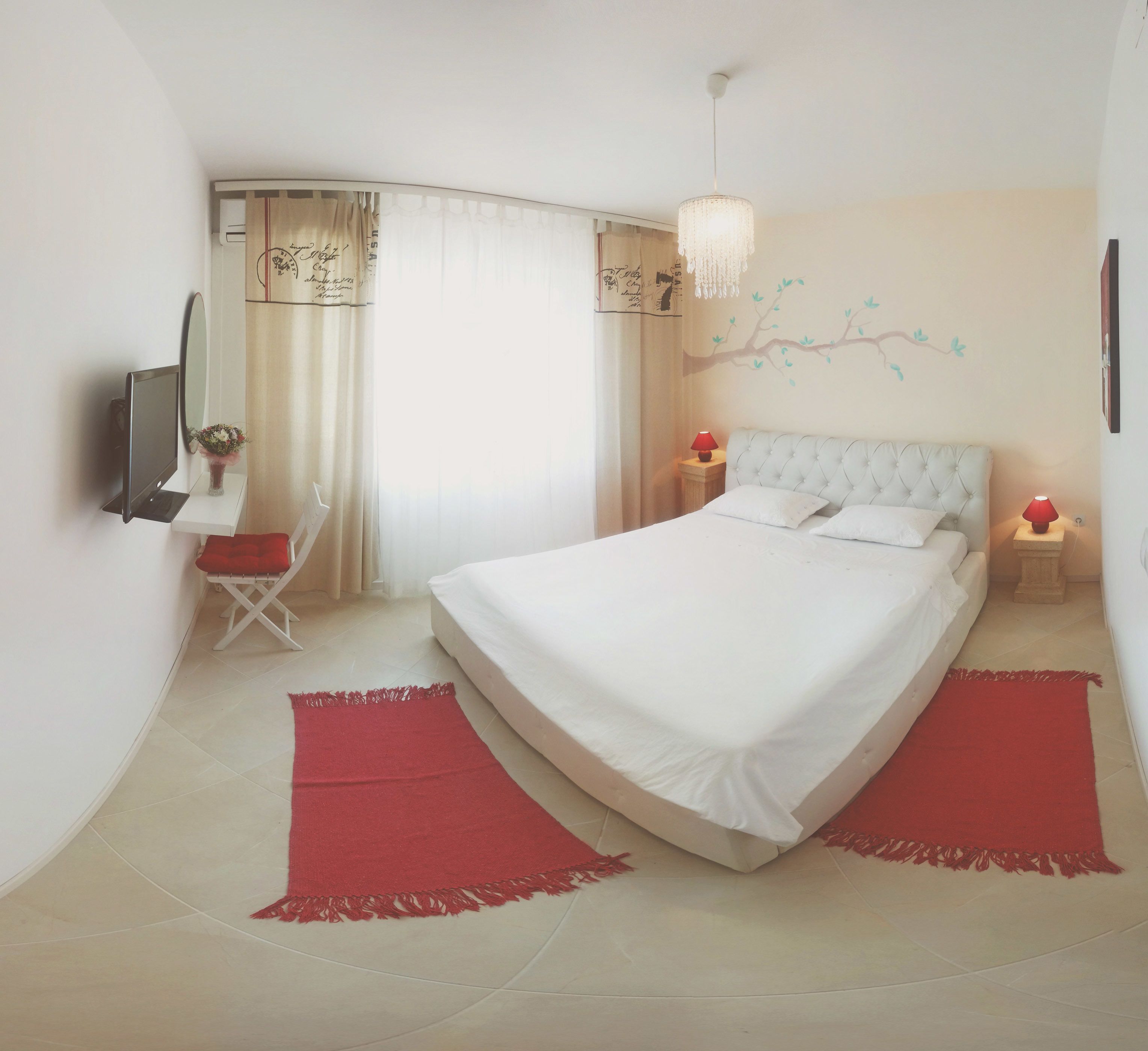 Quarto com cama grande, uma cadeira, televisão e decoração na parede.
