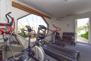 Ein Fitnessraum mit Laufbändern, Ergometer und einer Hantelbank.