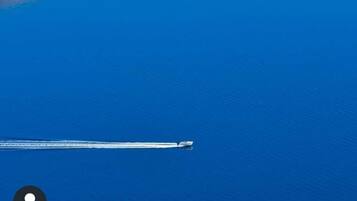 A boat moving across a calm blue body of water.