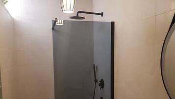 Un baño moderno con ducha de vidrio, inodoro blanco y lavamanos negro.