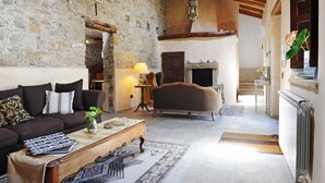 Una sala de estar acogedora con una pared de piedra, una chimenea, un sofá y una mesa de centro.