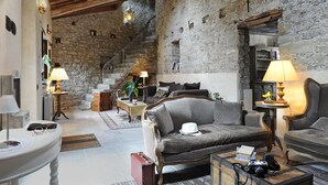 Una habitación acogedora y rústica con paredes de piedra, techo de madera y una mezcla de muebles modernos y clásicos.