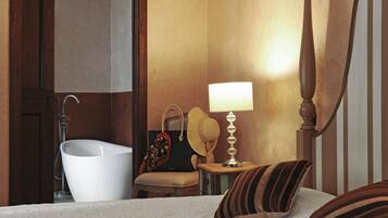 Ein Schlafzimmer mit Bett, Nachttisch, Nachttischlampe, einem Koffer und einem Badezimmer mit Badewanne.
