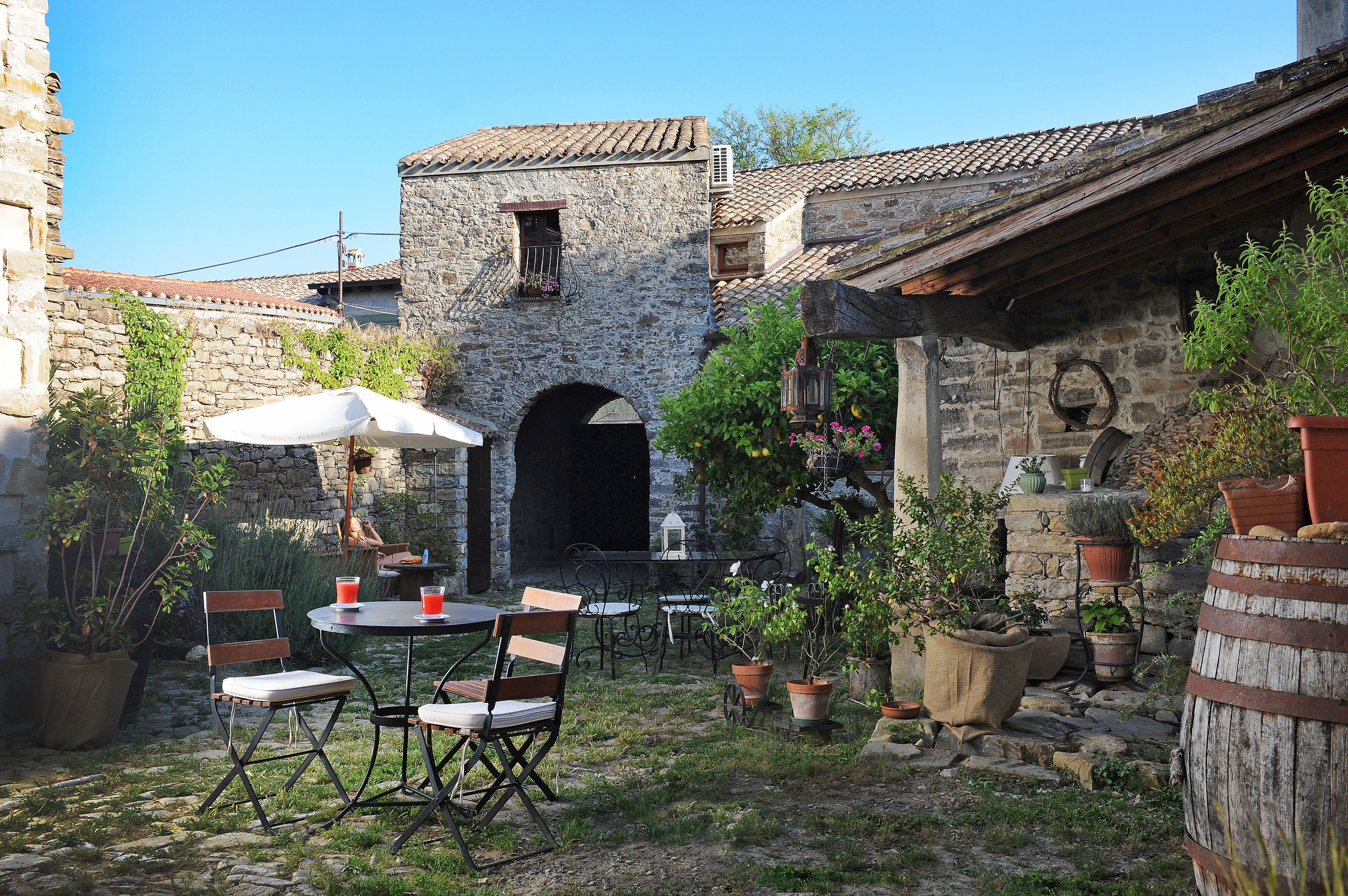 Un patio al aire libre con paredes de piedra, una mesa de madera rústica y plantas en macetas.