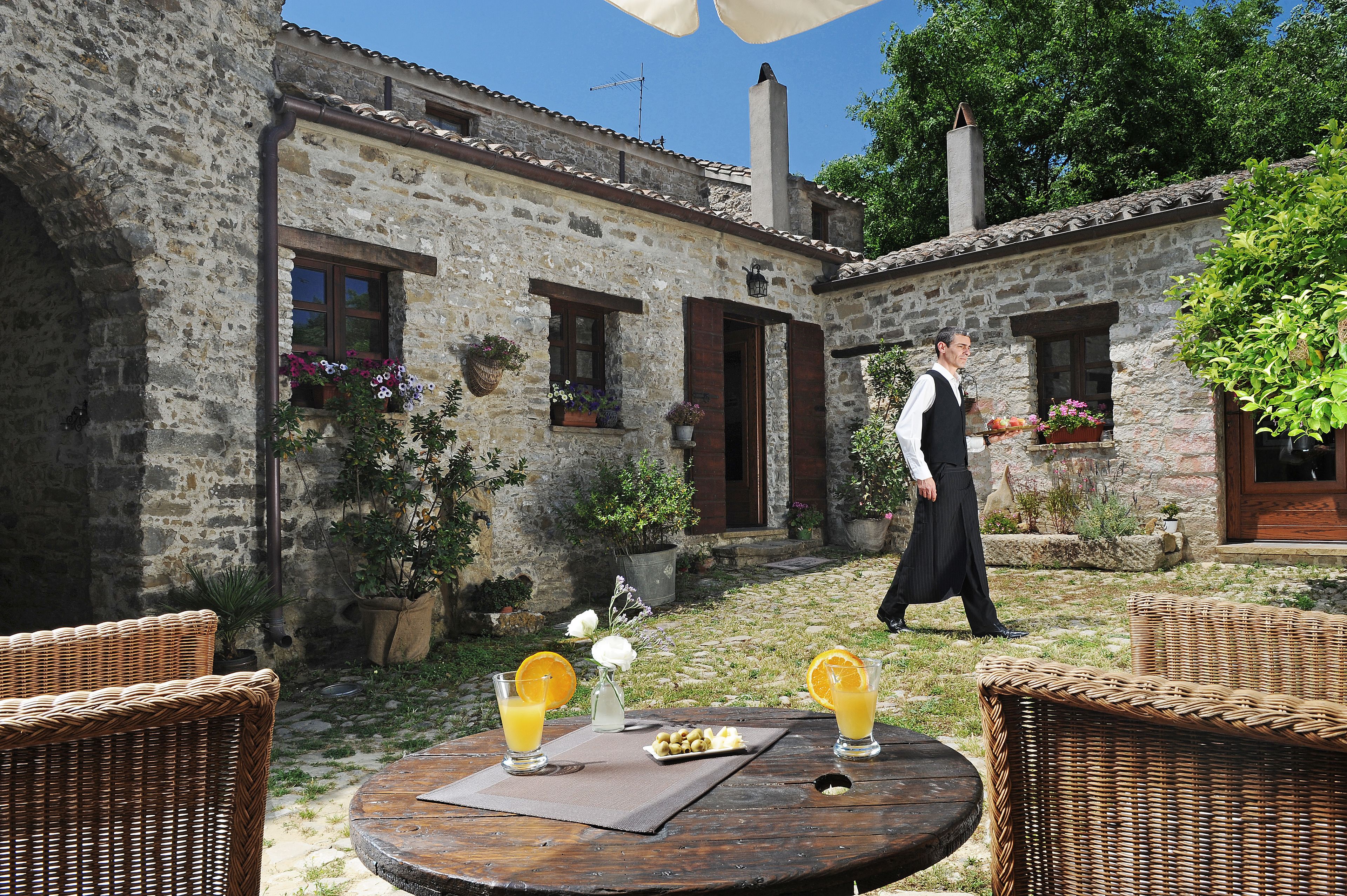 A stone building with a rustic exterior, outdoor seating with wicker furniture, and a table with drinks and snacks.